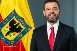 Retrato de Carlos Fernando Galán frente a la bandera de Bogotá, relacionado con la Reforma Tributaria 2025.