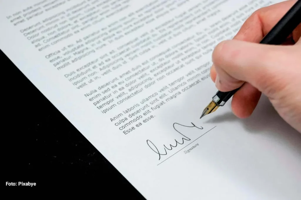 Mano firma documento oficial en hoja impresa, representando la falta de resultados concretos en la renegociación del TLC.
