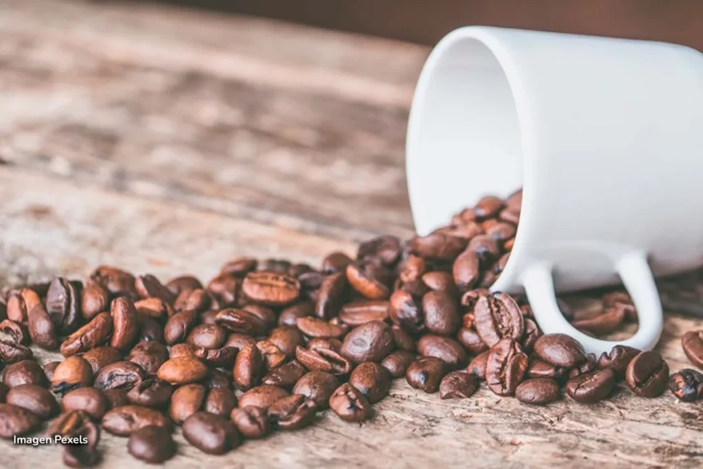 Las cafeterías bogotanas demuestran su talento en el Coffee Master 2025 2 Granos de café derramados desde una taza sobre mesa rústica.
