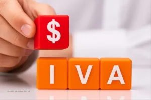 Cubos con letras IVA y símbolo de dinero sobre mesa, representación visual de la reforma tributaria en Colombia.
