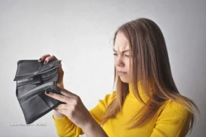 Mujer revisa billetera vacía, símbolo de pobreza monetaria en Colombia.