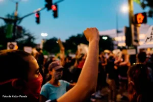 Persona con mascarilla levantando el puño durante manifestación en calle iluminada por semáforos en Colombia.