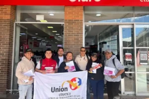 Integrantes de UTRATICS sostienen bandera y volantes frente a sede de Claro en jornada sindical, por aumento salarial