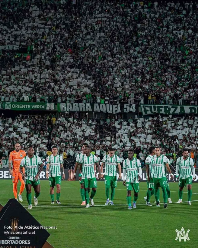 Jugadores de Nacional en el campo con tribuna de Los del Sur al fondo.