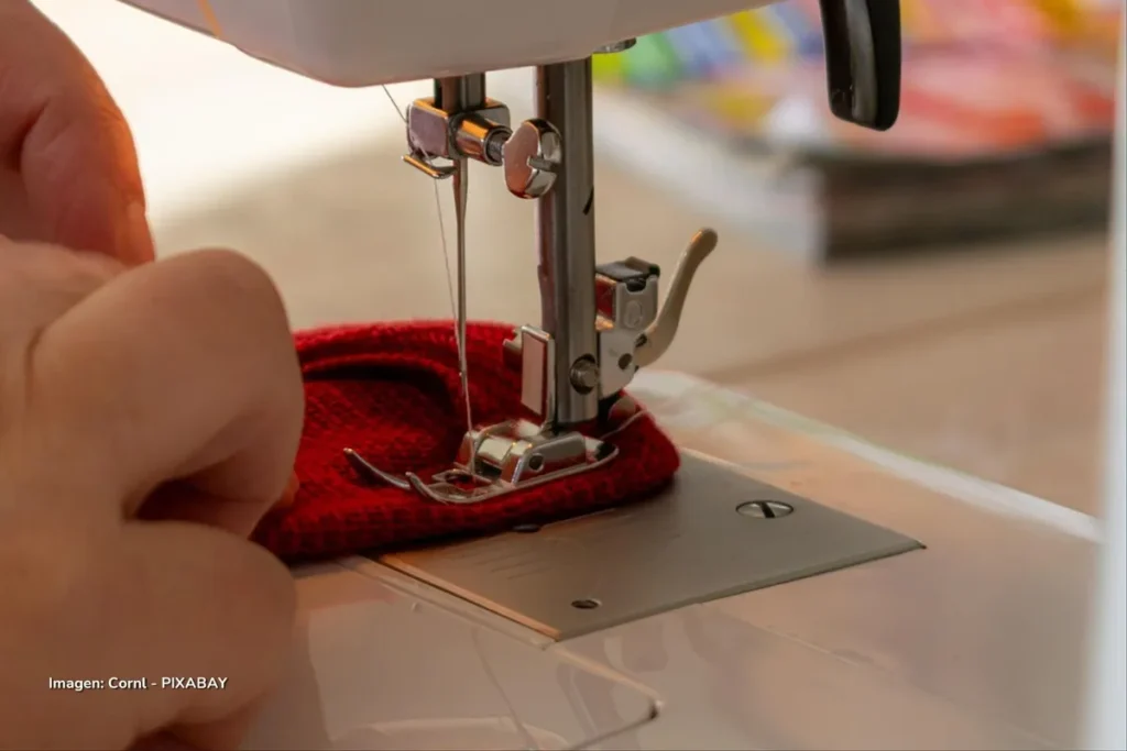 Persona utilizando máquina de coser en la confección textil, una de las actividades de la industria manufacturera colombiana.