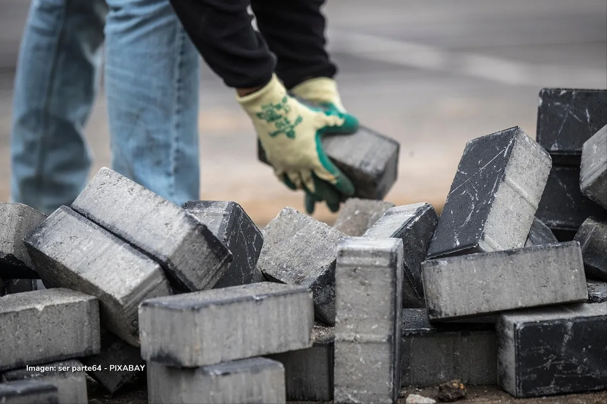 Obrero moviendo bloques de cemento simbolizando la recuperación de la construcción en Colombia.