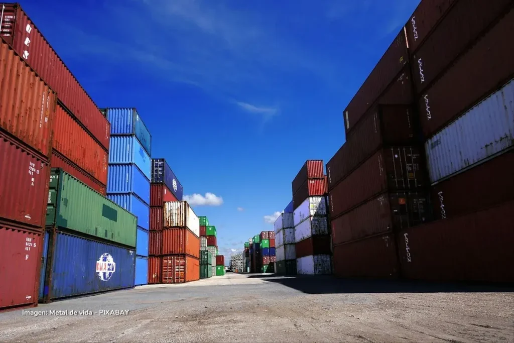 Contenedores apilados en puerto marítimo bajo cielo azul, ilustrando la balanza comercial de Colombia.