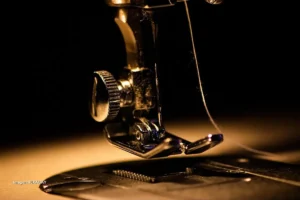 Máquina de coser en detalle con aguja e hilo, símbolo de la industria textil.