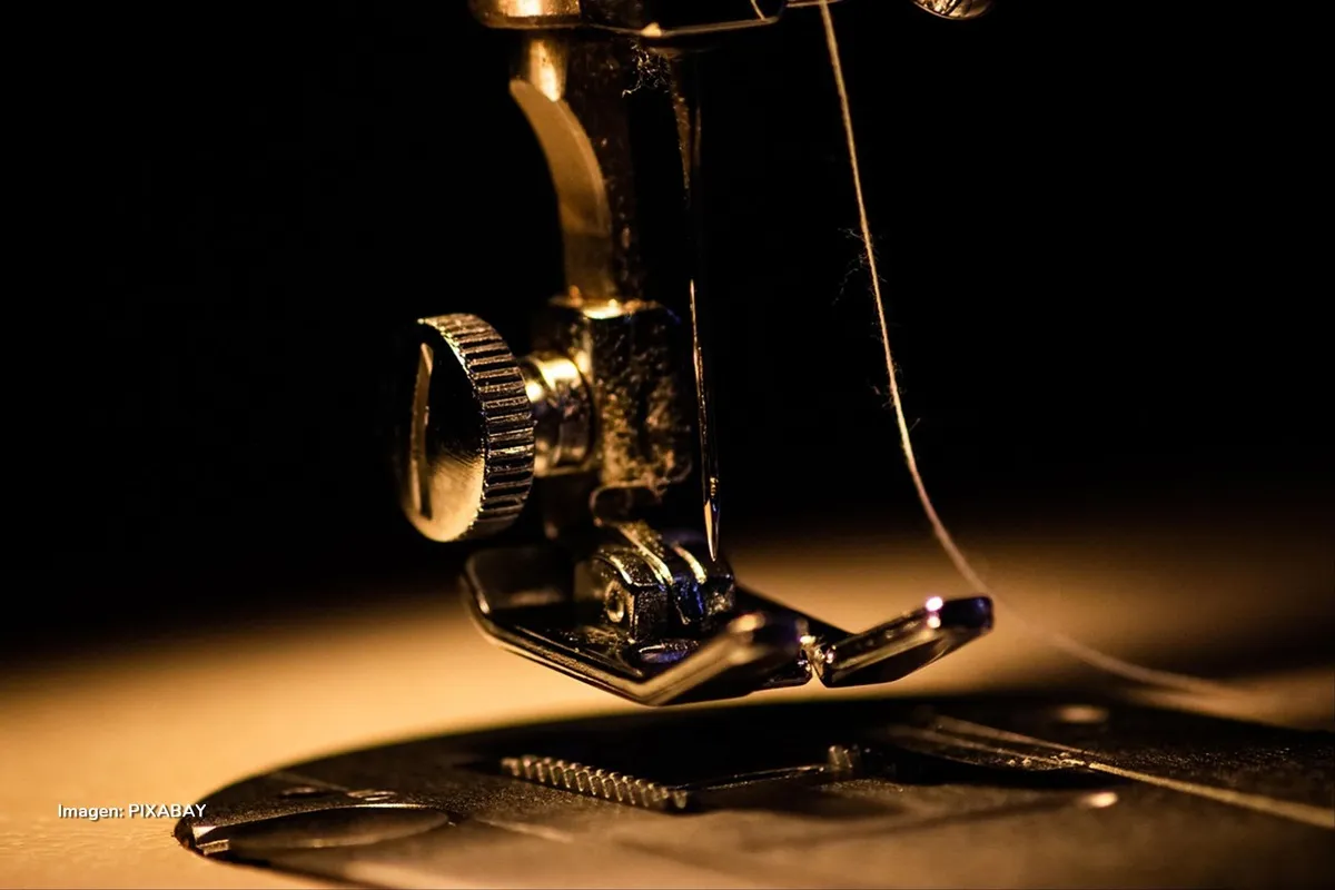 Máquina de coser en detalle con aguja e hilo, símbolo de la industria textil.