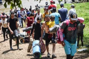 Personas migrantes cruzan un río con pertenencias, ilustrando los derechos de los migrantes.