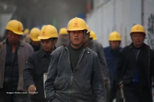 Trabajadores chinos con cascos amarillos reflejan el peso laboral en las importaciones chinas y la industria nacional.