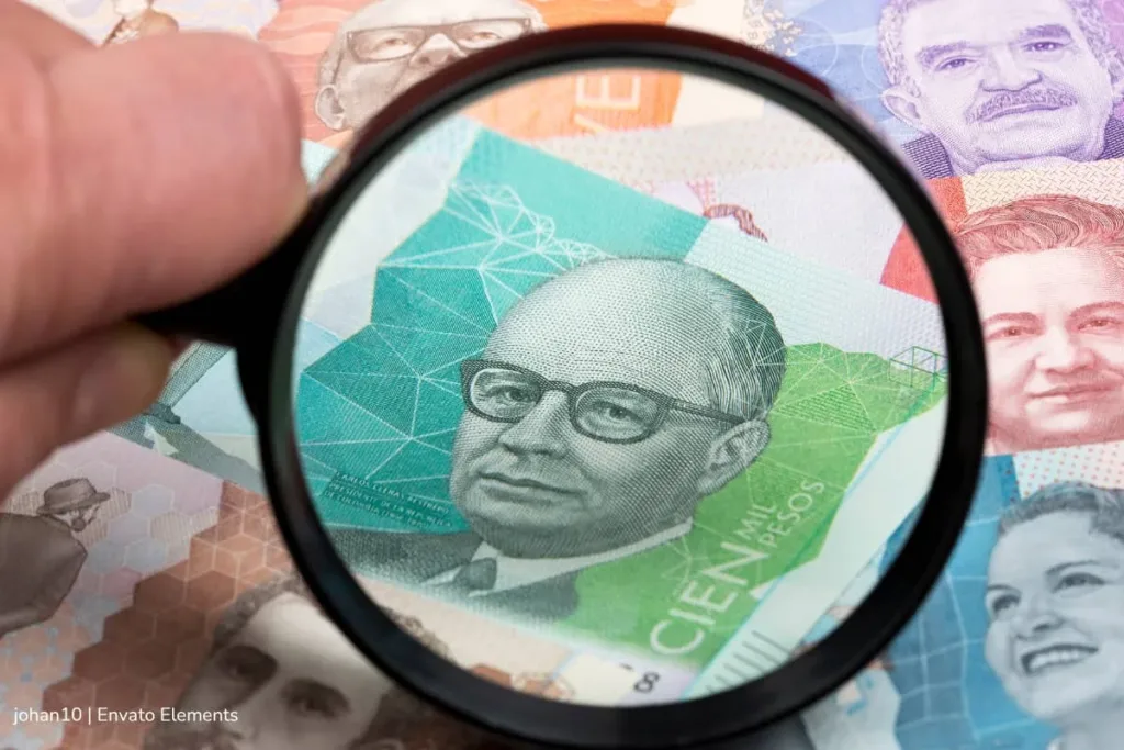 95.000 maestros pensionados temen por su prima de mitad de año: FOMAG usó plata de pensiones para cubrir salud 2 Lupa sobre billetes colombianos destaca el riesgo financiero que amenaza a la prima de mitad de año de pensionados.