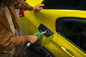 Hombre tanqueando un taxi amarillo en estación de servicio durante debate sobre la reforma tributaria de Petro.
