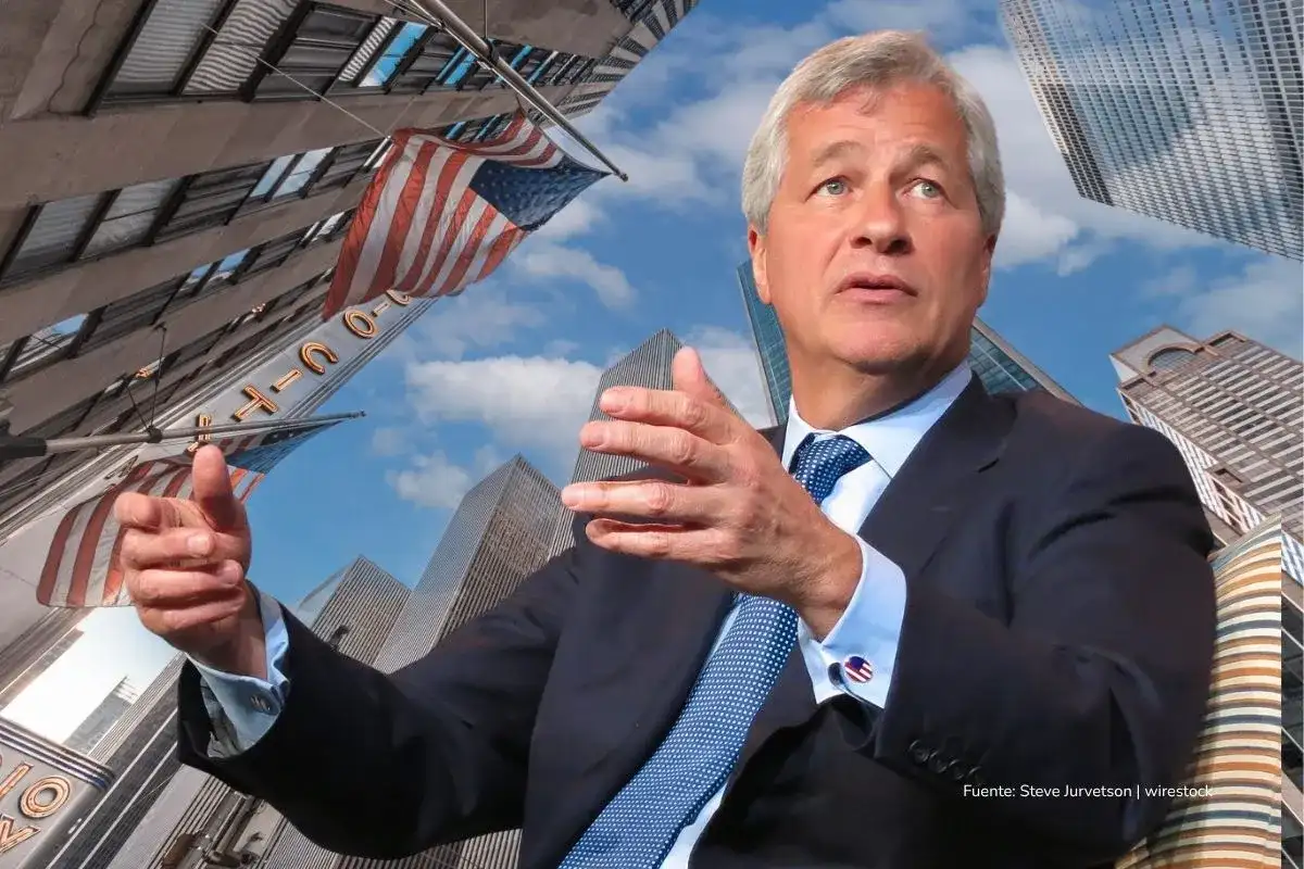 crisis Bancos de Estados Unidos 2025. Ejecutivo estadounidense en traje habla gesticulando, con edificios y banderas de Estados Unidos de fondo.