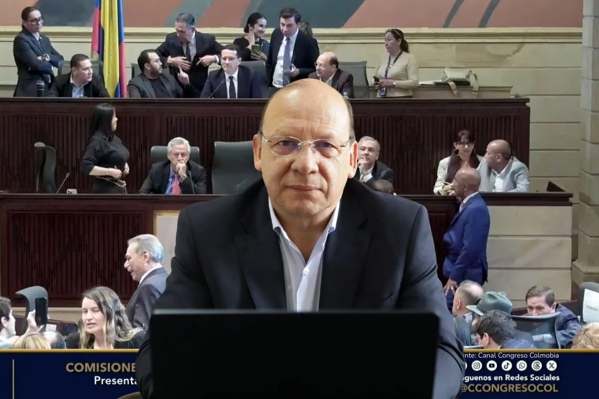 Ley de Financiamiento 2025. Hombre en un recinto legislativo aparece en primer plano mientras, al fondo, varios congresistas conversan y trabajan durante una sesión.