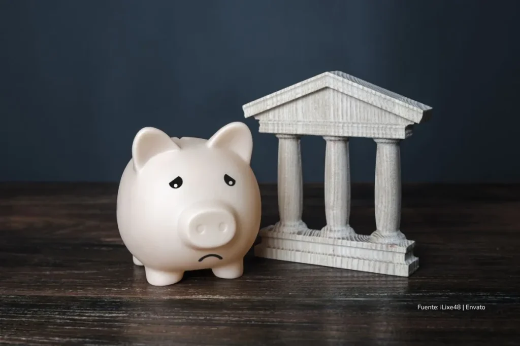 Bancos de Estados Unidos en líos por fraudes, quiebras y pérdidas millonarias que sacuden a Wall Street 3 Alcancía en forma de cerdito con expresión triste junto a una figura que representa un edificio bancario. crisis bancaria Estados Unidos 2025