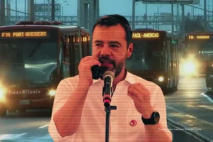 pasaje de transmilenio. Hombre hablando frente a micrófonos en un montaje donde aparecen buses de TransMilenio circulando en la vía.