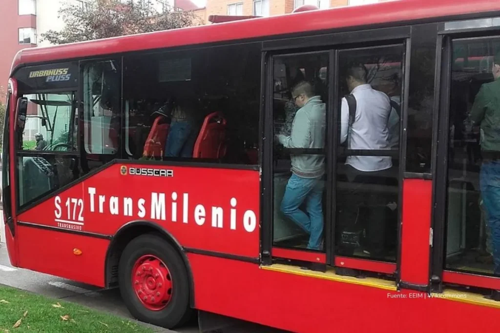 ¡Pasaje de TransMilenio subiría $250 en 2026! Galán pondrá a caminar a los bogotanos 3 Bus rojo de TransMilenio con varios pasajeros de pie y sentados dentro del vehículo.