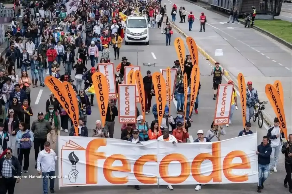 Gran multitud marcha por una avenida portando pancartas y banderas de Fecode durante una jornada de movilización.