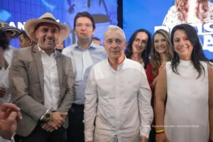 Elecciones 2026. Grupo de hombres y mujeres posando en un evento político sobre una tarima con pantalla de fondo.