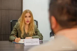 Puerto más eficiente del mundo. Funcionaria del Gobierno participa en una reunión de trabajo en oficina institucional, tomando notas durante un encuentro con otros asistentes.