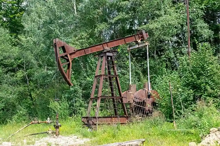 Exportaciones de Colombia 2025: transición energética frena el petróleo y aleja la meta de USD $50.000 millones 2 Estructura metálica oxidada de un viejo pozo petrolero ubicada en un área boscosa, rodeada de árboles y vegetación densa.