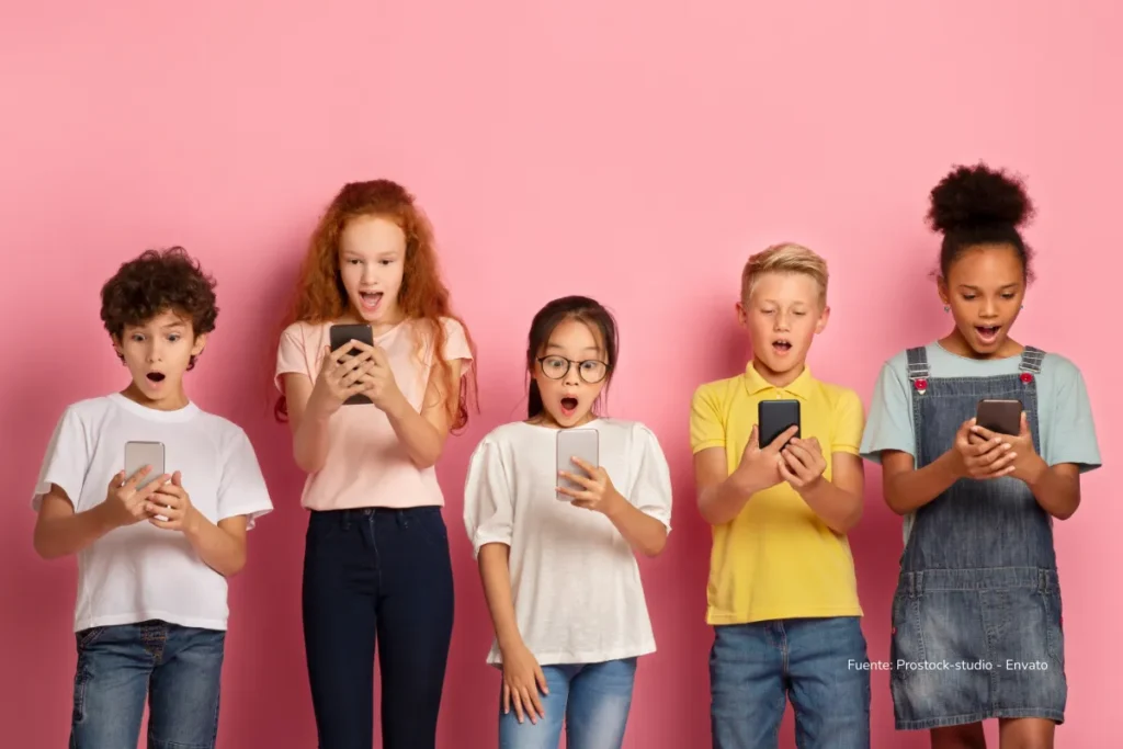 El mundo mira la ley de prohibición de las redes sociales en Australia: Alejará a millones de menores de TikTok e Instagram 3 Cinco niños de diversas edades y orígenes sostienen teléfonos móviles y observan la pantalla con expresiones de sorpresa, frente a un fondo rosado.