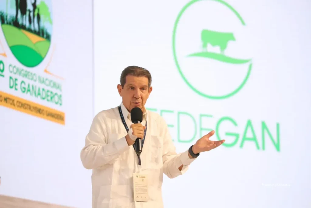 El hijo de José Félix Lafaurie y María Fernanda Cabal habría recibido subsidio de Finagro como “pequeño productor” 4 Hombre sostiene un micrófono y habla en un escenario durante un evento del sector ganadero, con el logo de Fedegán al fondo.