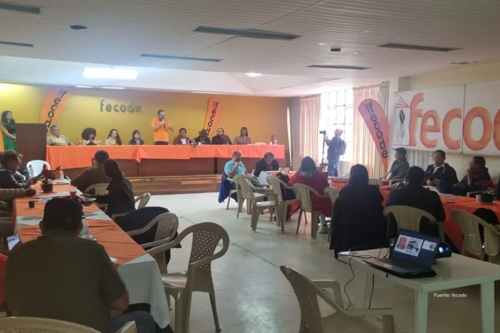 Crisis del Fomag: el sistema improvisado que hoy tiene a ministros en juicio y a miles de maestros sin atención 4 Asamblea con participantes sentados frente a una mesa principal, durante un evento de deliberación y toma de decisiones en un salón comunal.