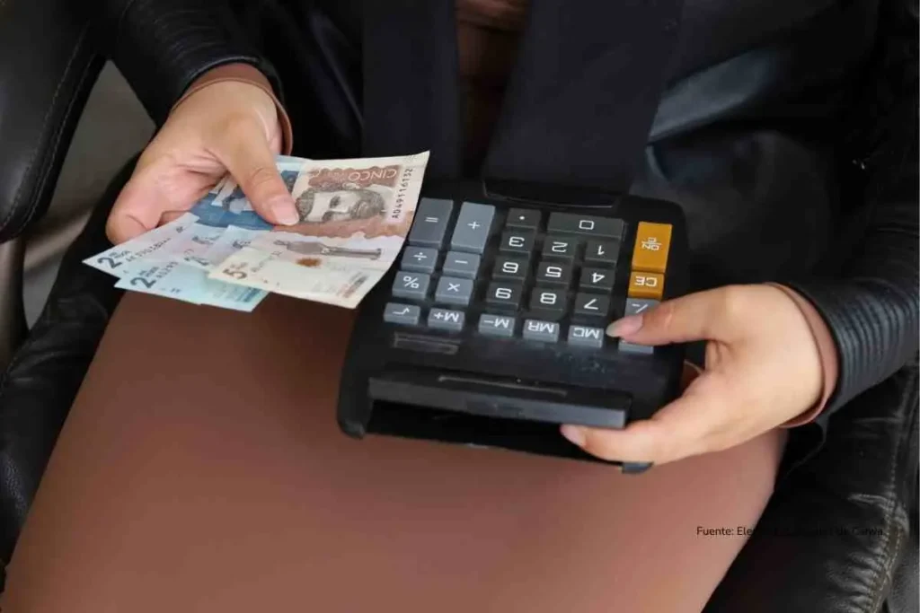 Multas hasta $500.000 por ruido excesivo: lo que dice la ley para este diciembre 3 Primer plano de una mano con billetes colombianos y una calculadora