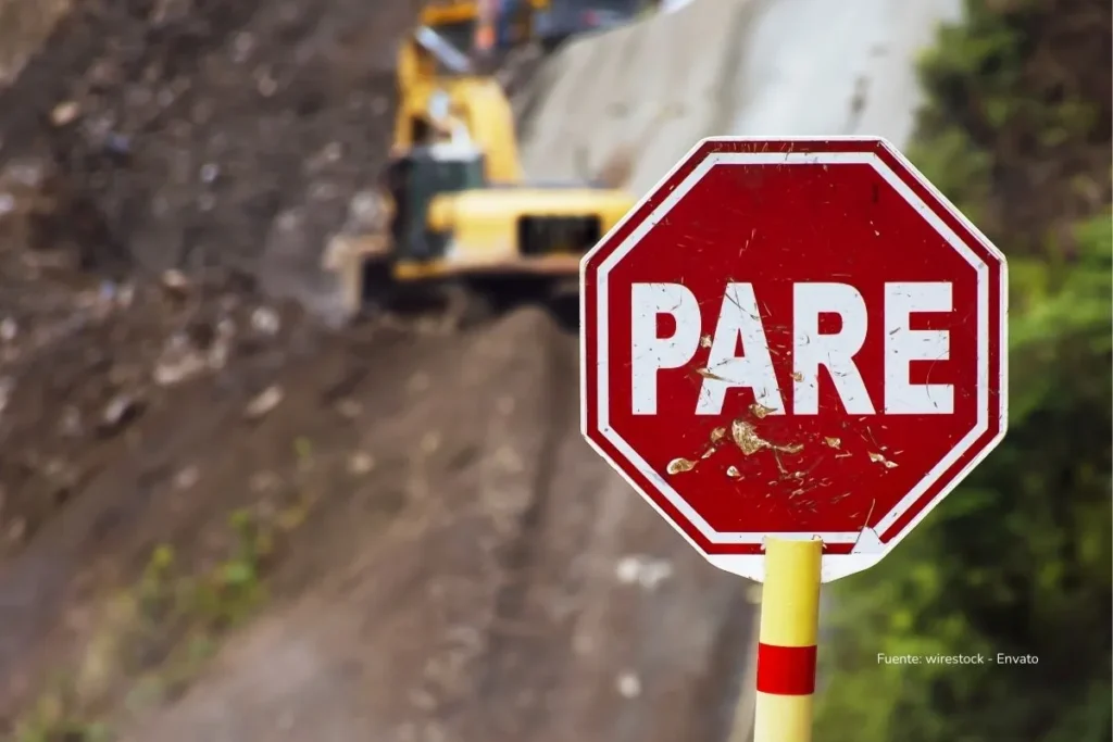 Crisis fiscal Colombia: los tres caminos que le quedan al Gobierno tras el hundimiento de la reforma tributaria 2 Señal de tránsito de “PARE” frente a maquinaria trabajando en una obra vial en terreno inestable.