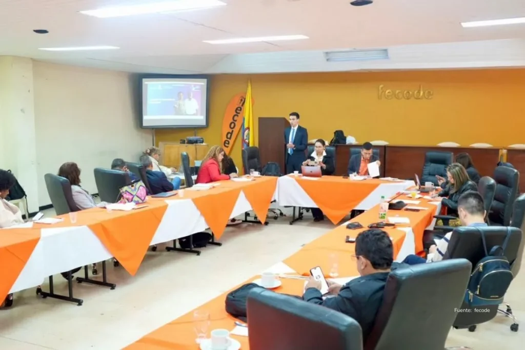 Pacientes mueren esperando medicamentos en Colombia, mientras el Gobierno de Petro y EPS se culpan 2 Conferencia empresarial con un expositor presentando datos en pantalla frente a asistentes sentados en mesas de trabajo. medicamentos en Colombia, EPS, gobierno de Petro