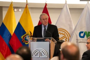 Comunidad Andina. Funcionario interviene desde un atril con banderas de países andinos y de un organismo regional al fondo