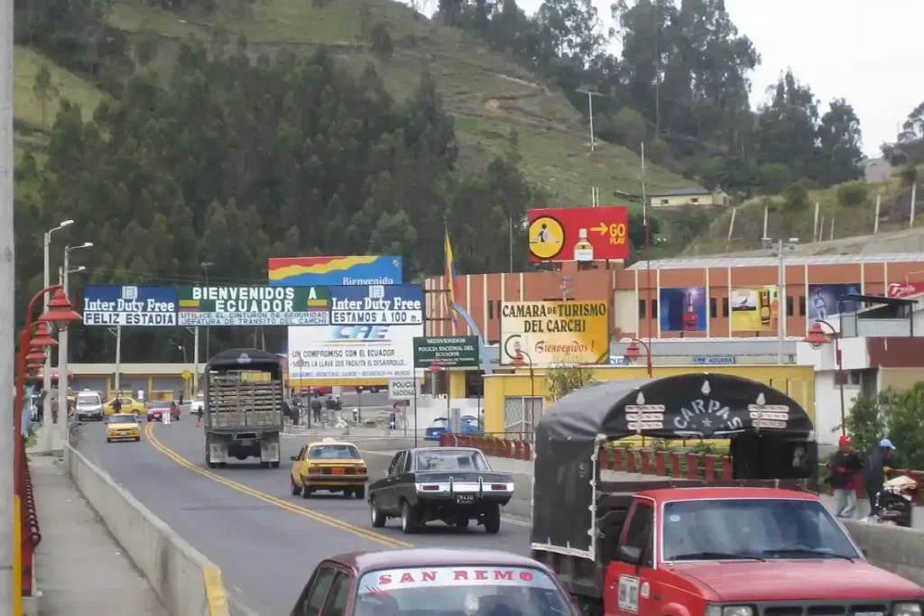 Aranceles de Colombia a Ecuador: el decreto que redefine el comercio bilateral 3 Tránsito de vehículos en un paso fronterizo entre Colombia y Ecuador con señalización comercial y turística
