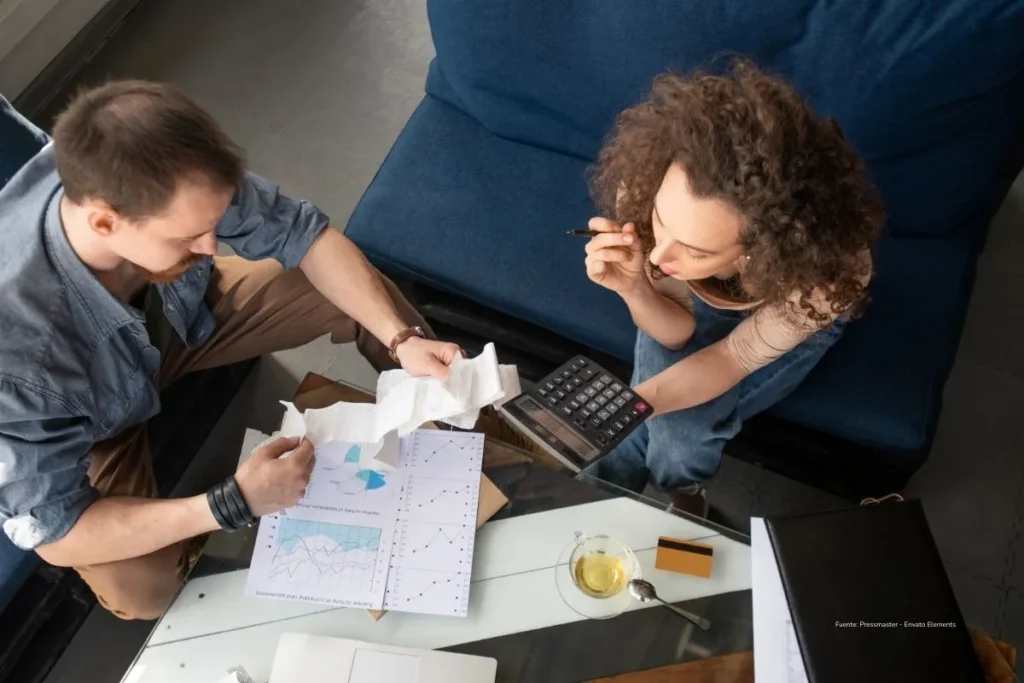 Así cambia el pago de cesantías en 2026 tras la reforma laboral en Colombia 2 Dos personas revisan facturas y documentos financieros mientras usan una calculadora en una mesa