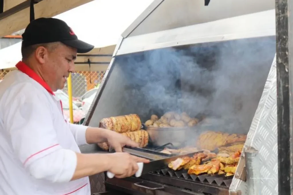 Inflación de enero en 2026: por qué el ‘corrientazo’ y el transporte anticipan meses más caros 2 Trabajador prepara carne a la parrilla en un puesto de comida mientras sale humo del asador