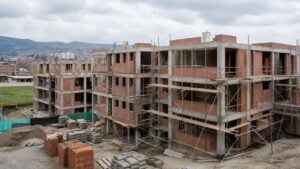 Edificio de vivienda en construcción con andamios, ladrillo y sacos de cemento