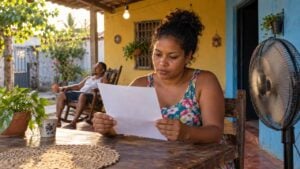Mujer revisa un papel junto a un ventilador en el patio de una casa del Caribe colombiano