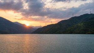 Embalse colombiano al atardecer con líneas eléctricas entre montañas