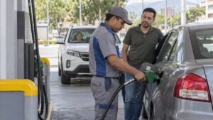 Trabajador llena el tanque de un carro mientras el conductor espera en una estación colombiana