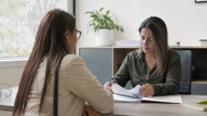 Persona realiza un trámite con una funcionaria en una oficina administrativa serena.