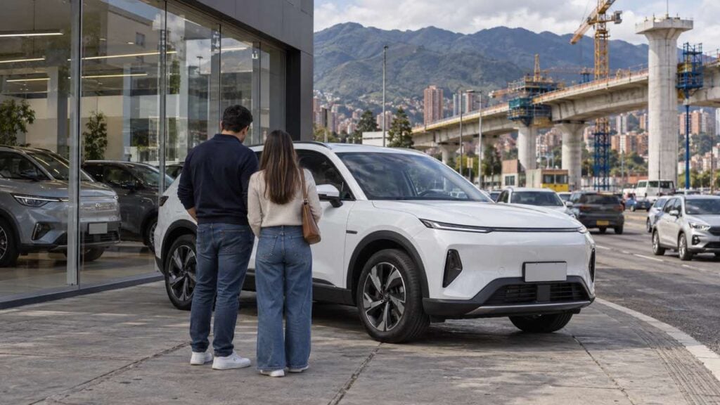 Pareja observa un vehículo eléctrico en una avenida bogotana con un viaducto en construcción al fondo