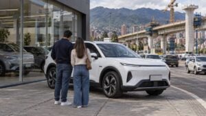 Pareja observa un vehículo eléctrico en una avenida bogotana con un viaducto en construcción al fondo