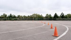 Pista de práctica de conducción vacía con conos naranjas sobre el asfalto