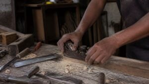 Manos de trabajadores en un pequeño taller colombiano iluminado por la luz del amanecer