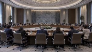 Delegados ficticios sentados de espaldas alrededor de una mesa circular en una sala internacional