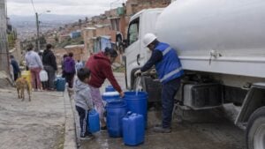 Una vecina y un niño llenan bidones con agua de un carrotanque en un barrio de ladera del suroriente de Bogotá.