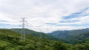 Torres de transmisión eléctrica de alta tensión sobre lomas verdes en una zona andina