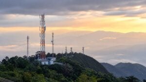 Torres de telecomunicaciones sobre un paisaje montañoso colombiano con niebla al atardecer