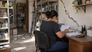 Comerciante revisa documentos en la oficina de un pequeño negocio con una grieta en la pared